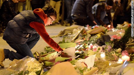 A boy lights candles outside Le Carillon bar, the day after a deadly attack on November 14, 2015 in Paris, France. At least 120 people have been killed and over 350 injured, 99 of which seriously, following a series of terrorist attacks in the French capital.