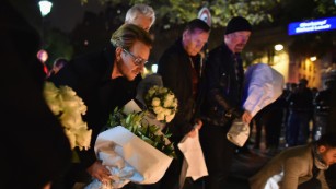 PARIS, FRANCE - NOVEMBER 14:  Bono and band members from the band U2 place flowers on the pavement near the scene of yesterday's Bataclan Theatre terrorist attack on November 14, 2015 in Paris, France. At least 120 people have been killed and over 200 injured, 80 of which seriously, following a series of terrorist attacks in the French capital.  (Photo by Jeff J Mitchell/Getty Images)