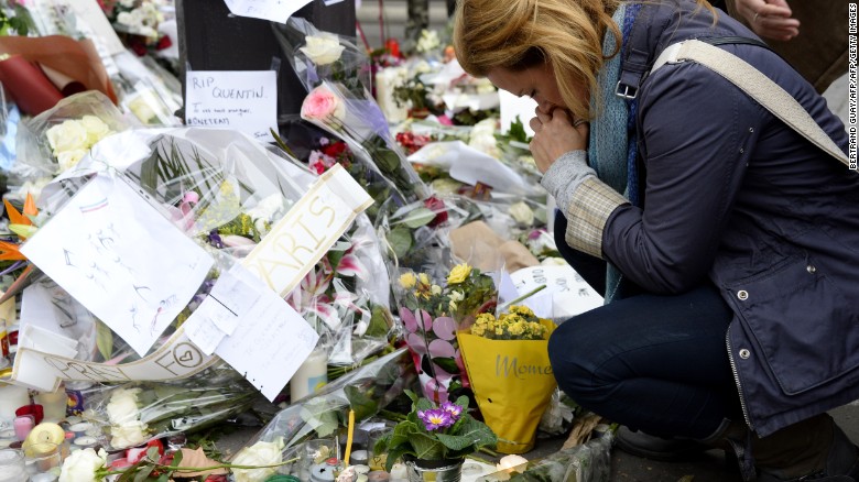 A woman takes a moment to pay her respects ahead of a minute of silence on November 16, 2015 at the Bataclan concert hall in Paris.