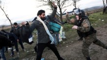 A Macedonian police officer hits a man with his baton near Idomeni at the Greek-Macedonian border -- this is part of the so-called Balkans Route to northern Europe.