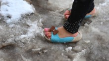 As the first snows of the season fall in Germany, a sandalled refugee girl plays in front of a former army barracks now serving as a shelter for asylum seekers.