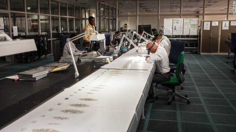 De Beers employees inspect diamonds aggregated from the company&#39;s global supply in Gaborone, Botswana. The company moved 82 experts and their families from London to set up the facility in 2013.