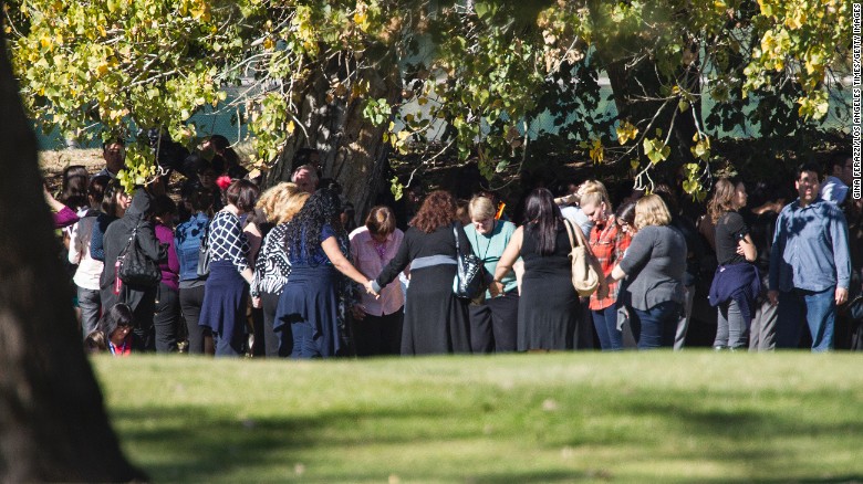 People pray on the San Bernardino Golf Course, across the street from where the shooting took place.