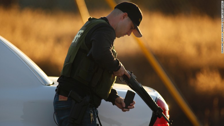 A police officer loads his weapon while pursuing suspects.
