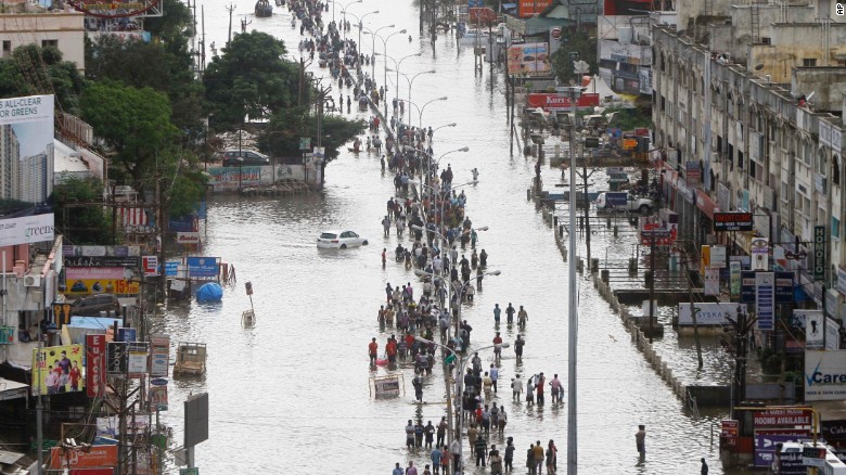 People walk through a flooded street in Chennai, India, Thursday, December 3, 2015. Heaviest rainfalls in more than 100 years have devastated swathes of the southern Indian state of Tamil Nadu, with thousands forced to leave their submerged homes and schools, offices.