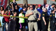 A crowd gathers behind police line near the scene of a shooting on December 2, 2015 in San Bernardino, California. One or more gunman opened fire inside a building in San Bernardino in California, with reports of 20 victims at a center that provides services for the disabled. Police were still hunting for the shooter, saying one to three possible suspects were involved. Heavily armed SWAT teams, firefighters and ambulances swarmed the scene, located about an hour east of Los Angeles, as police warned residents away.  AFP PHOTO / FREDERIC J. BROWN / AFP / FREDERIC J. BROWN        (Photo credit should read FREDERIC J. BROWN/AFP/Getty Images)