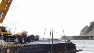 Japanese coast guard pull the wooden boat from the water.