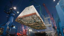 The 1,000-ton deckhouse is craned toward the deck of the ship to be integrated with the its hull at Bath Iron Works on December 14, 2012.