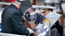Retired Marine Corps Lt. Col. James G. Zumwalt, left, assists welder Carl Pepin as he inscribes a steel plate at a keel laying ceremony at Bath Iron Works on Thursday, November 17, 2011.