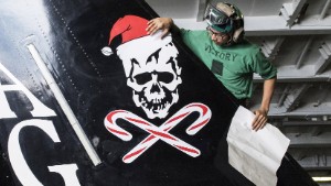 151213-N-ZG705-001 MEDITERRANEAN SEA (Dec. 13, 2015) Aviation Structural Mechanic Airman V. Sek, assigned to the "Jolly Rogers" of Strike Fighter Squadron (VFA) 103, applies a Christmas decal to an F/A-18F Super Hornet in the hangar bay of aircraft carrier USS Harry S. Truman (CVN 75). Harry S. Truman Carrier Strike Group is conducting naval operations in the U.S. 6th Fleet area of operations in support of U.S. national security interests in Europe and Africa. (U.S. Navy photo by Mass Communication Specialist 2nd Class K. H. Anderson/Released)
