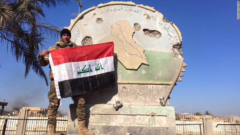 An Iraqi soldier holds a national flag in the government complex in central Ramadi, 70 miles (115 kilometers) west of Baghdad, Iraq, Monday, Dec. 28, 2015. Iraqi military forces on Monday retook a strategic government complex in the city of Ramadi from Islamic State militants who have occupied the city since May. (AP Photo)
