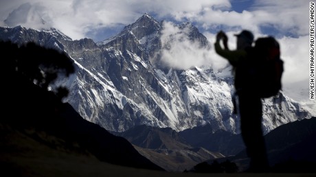 A tourist takes pictures as Mount Everest, left, is covered with clouds in Nepal's Solukhumbu district, also known as the Everest region.