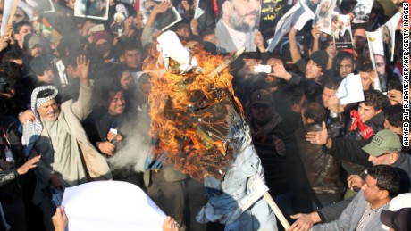 Supporters of Iraqi Shiite cleric Moqtada al-Sadr (portrait top-C) burn a effigy of a member of the Saudi ruling family as others hold posters of prominent Shiite cleric Nimr al-Nimr during a demonstration in the capital Baghdad on January 4, 2016, against Nimr&#39;s execution by Saudi authorities. Sunni-ruled Saudi Arabia severed diplomatic ties with Shiite-dominated Iran, its long-time regional rival, after angry demonstrators attacked the Saudi embassy in Tehran and its consulate following Nimr&#39;s execution. AFP PHOTO / AHMAD AL-RUBAYE / AFP / AHMAD AL-RUBAYE        (Photo credit should read AHMAD AL-RUBAYE/AFP/Getty Images)