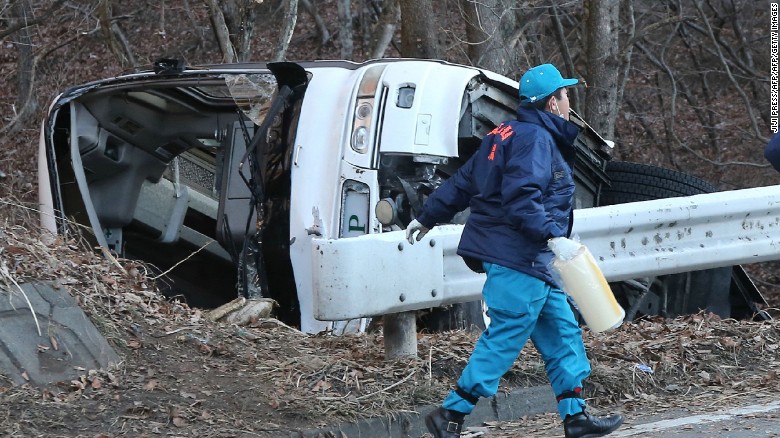 An investigator walks beside the bus wreckage on January 15, 2016. The tour bus veered off the road on the way to a ski resort in central Japan.