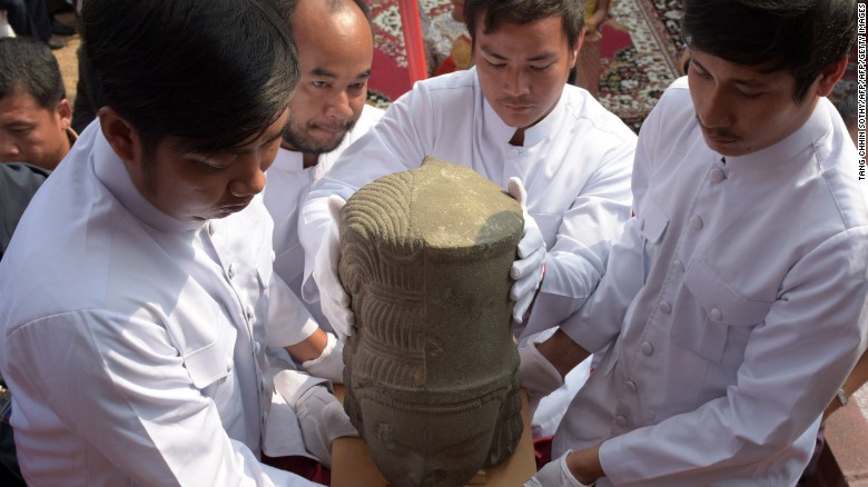 Museum employees carry the head of the Harihara statue during a ceremony connecting the head to the body.