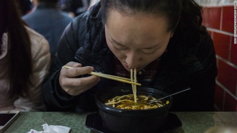 A woman eats noodles in a restaurant in Beijing in this file photo from November 2014. 