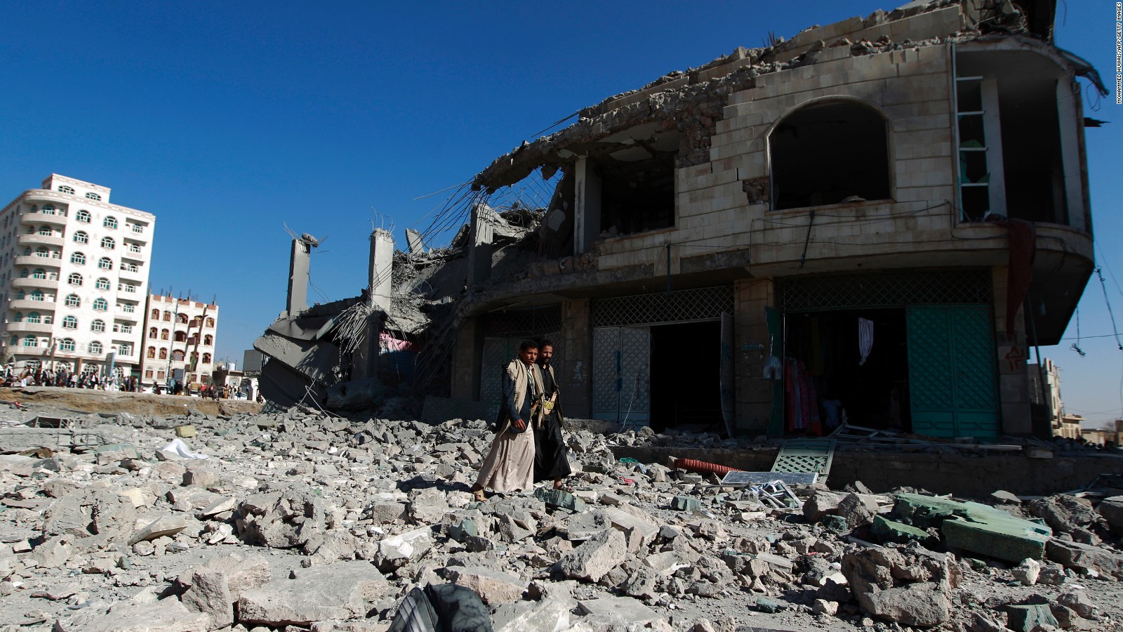 Yemenis walk past the site of a Saudi-led airstrike in Sanaa on January 25, 2016.