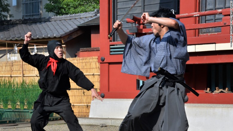 Members of a pantomime group clad in a samurai (L) and ninja (R) costumes perform in Tokyo.