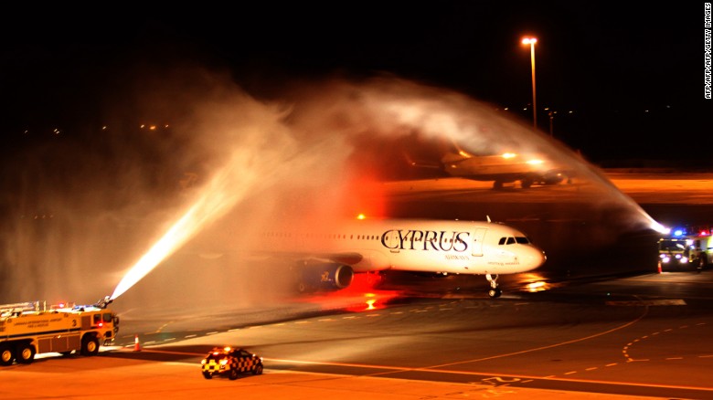 The plane carrying Pavlos Kontides taxies under a victory water arch laid on by the fire service after landing at Larnaca Airport.