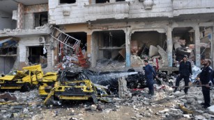 Firefighters spray water on a burning car at the bombing site in Homs.