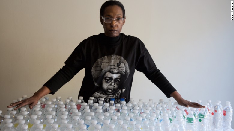 Gina Luster in her Flint, Michigan home with the total bottles of water it takes to get through a day.