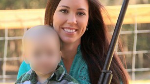 Jamie Gilt posing with a gun and small child. 