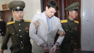 Warmbier gets escorted Wednesday at the North Korean Supreme Court. 