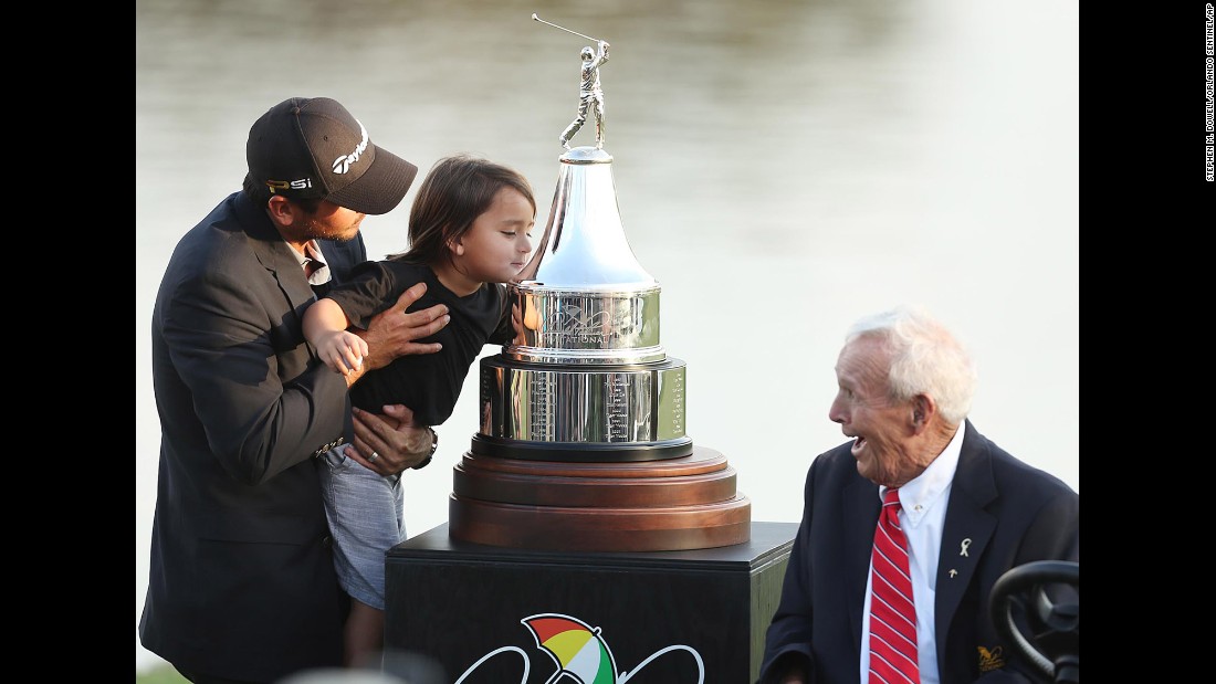 Legendary golfer Arnold Palmer smiles as Jason Day&#39;s son, Dash, kisses the trophy his dad got for winning the Arnold Palmer Invitational on Sunday, March 20.