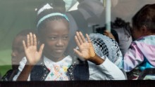 A young girl looks out of the window of a bus after being evacuated from the airport.