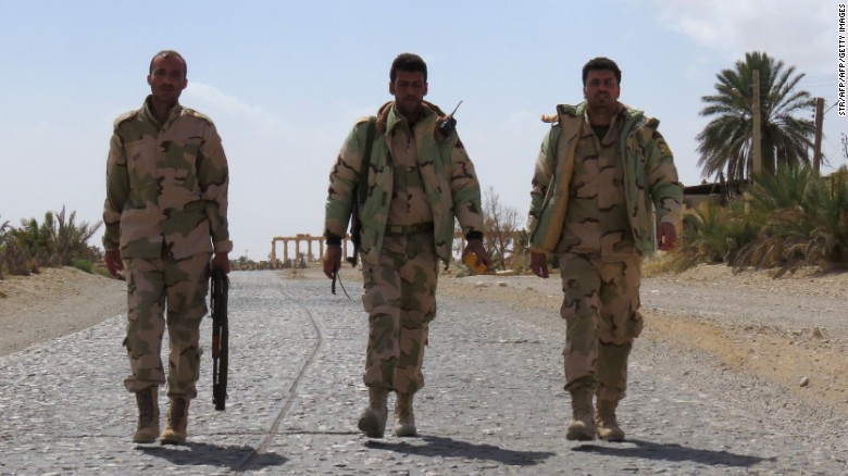 Syrian pro-government forces walk on a street in the ancient city of Palmyra on March 27, 2016, after troops recaptured the city from ISIS.