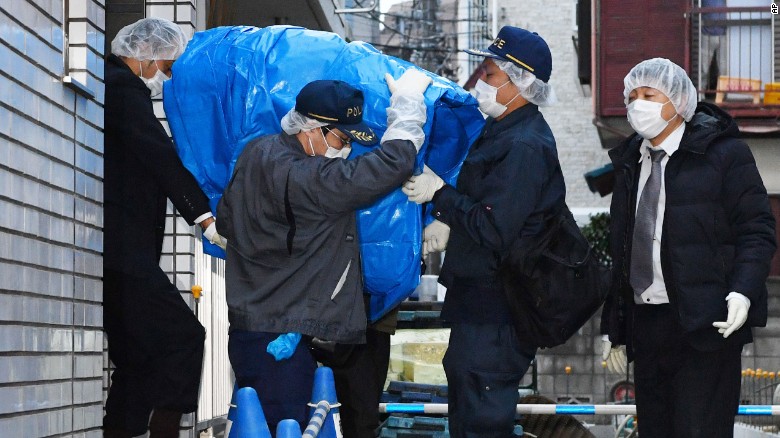 Police officers carry a sheet-covered computer from the apartment of abduction suspect Kabu Terauchi on Monday.