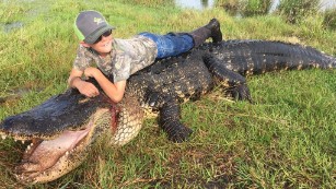 Mason Lightsey lays on top of the alligator that was hunted at Outwest Farms in Florida.