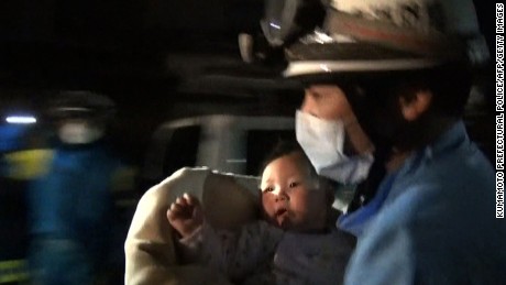 A rescue worker carries an eight-month-old baby girl after she was pulled from the rubble following the earthquake in Mashiki, Kumamoto Prefecture. 