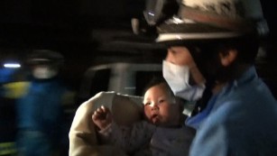 A rescue worker carries an eight-month-old baby girl after she was pulled from the rubble following the earthquake in Mashiki, Kumamoto Prefecture. 