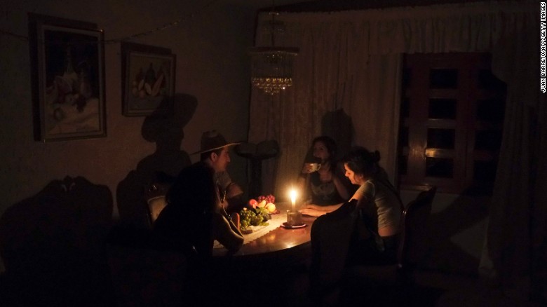 A family sit at a candle lit table in the state of Barinas, Venezuela on April 25.
