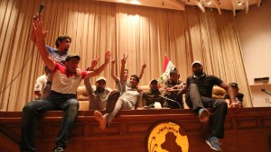 Iraqi protesters flash the V-sign as they gather inside the parliament after breaking into Baghdad&#39;s heavily fortified green zone on Saturday, April 30. 