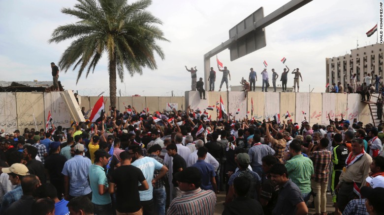 Supporters of Shiite cleric Muqtada al-Sadr walk over the blast walls surrounding Baghdad&#39;s highly fortified Green Zone Saturday, April 30, 2016. 