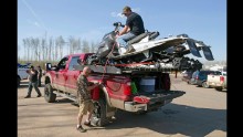 Robert Parker, left, and Matt Jones siphon gas from two snowmobiles for their truck on May 4.