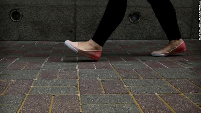 A woman walks over the sidewalk reinforced with glue to prevent the bricks from being dug up and used as projectiles. 