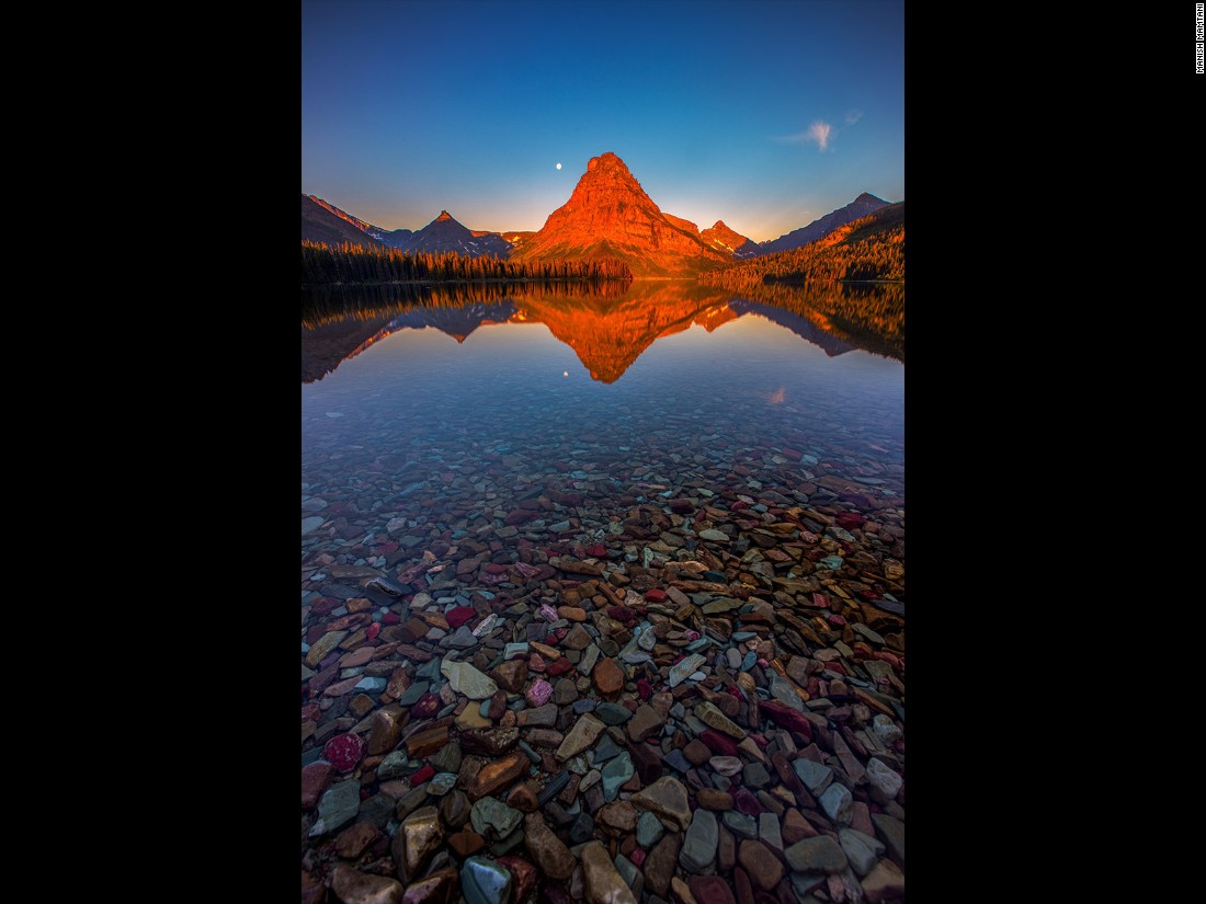Manish Mamtani made a pre-dawn mission to Two Medicine Lake, Glacier National Park, Montana, to capture this sunrise. "There were no clouds but the lake water was so calm, it created a perfect reflection of the red light kissing the Sinopah Mountain," he says. (<a href="http://travel.nationalgeographic.com/photographer-of-the-year-2016/" target="_blank">Click here to enter NatGeo photo contest</a>)