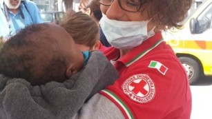 An Italian Red Cross worker holds a rescued migrant baby who arrived in Messina, Italy. 
