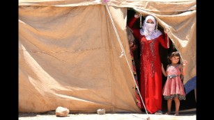 Internally displaced Iraqis peer out of a tent at a camp outside Falluja, Iraq, on Monday, June 14.