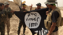 Group of Iraqi soldiers proudly pick up ISIS flag left behind