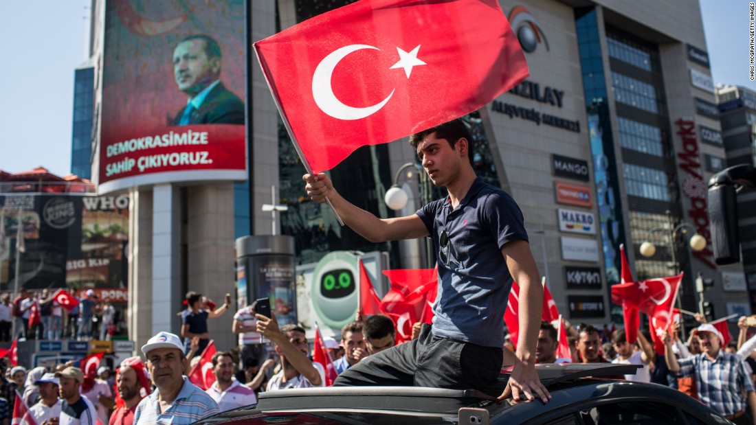A man waves a Turkish flag from the roof of a car during a march around Kizilay Square on Saturday July 16 in Ankara, Turkey, in reaction to the attempted military coup. 