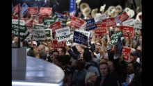 Delegates hold signs on the floor of the convention.