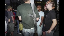 A calm conversation takes place in Public Square with a man wearing a gun.