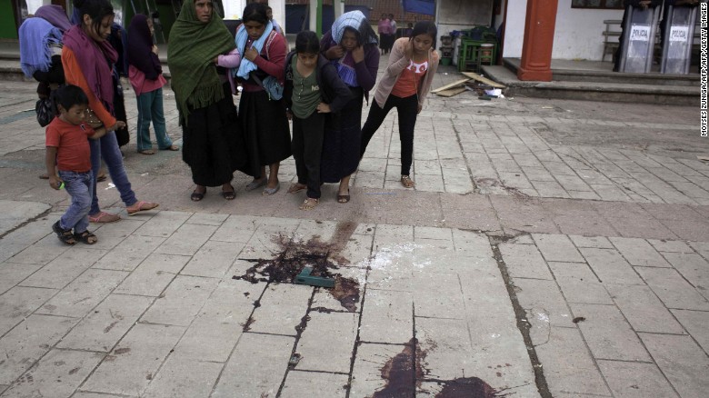 Indigenous people look at blood on the pavement in the site where Mayor Domingo Lopez Gonzalez was killed during a protest in San Juan Chamula, Chiapas state, Mexico.