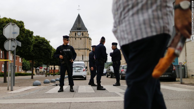 Police officers stand guard Wednesday at the Catholic church where the priest was slain.