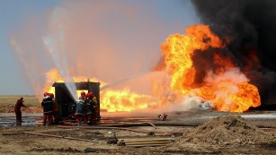 Oil workers and firemen try to extinguish flames at the Khabbaz oil field near Kirkuk on June 1 after an attack.