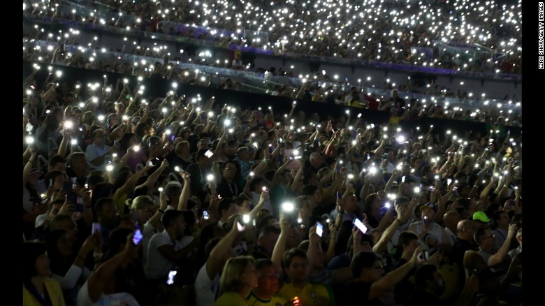 Spectators hold up their phones during the event.